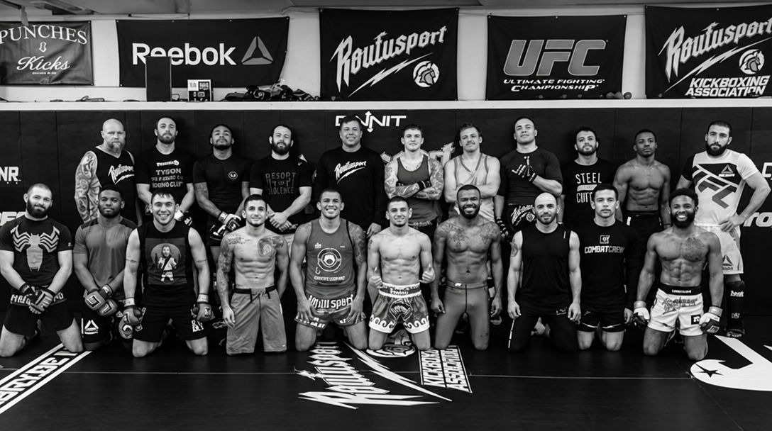 A group of combat sports athletes lined up on the gym mats, photographed in black and white.