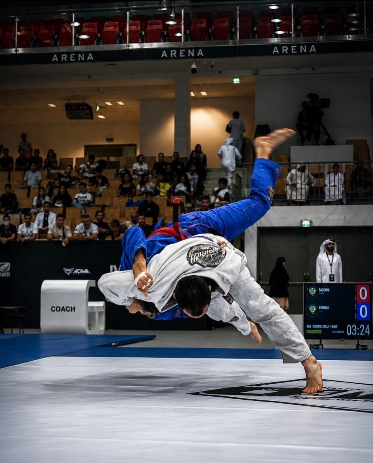 Two Brazilian jiu-jitsu athletes executing a throw during competition
